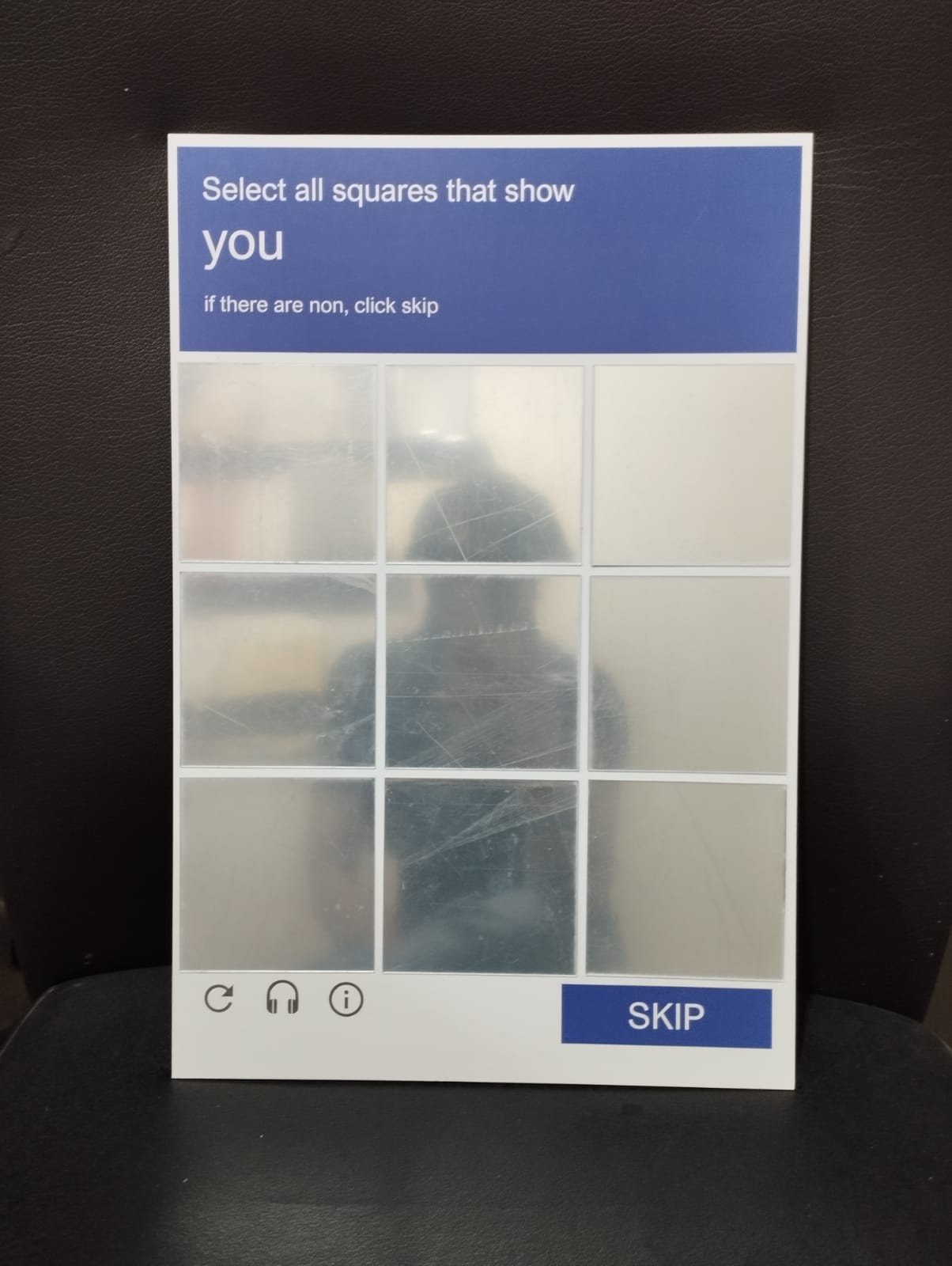 Close-up of CAPTCHA wall mirror with select-all-squares grid design, silver acrylic novelty mirror
